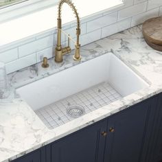 a white kitchen sink sitting under a faucet next to a marble counter top