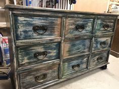 an old dresser has been painted blue and green with white streaks on the drawers, as well as black handles