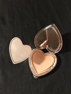 two heart shaped mirrors sitting on top of a black surface