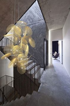 an artistic light fixture hanging from the side of a stair case in a modern house