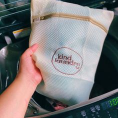 a person is holding a bag in front of an electric dryer with the word kindle laundry on it