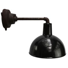 an industrial style wall light with a black metal shade on the arm and a white background