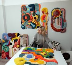 a woman sitting at a table in front of some art