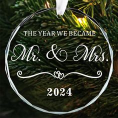 a glass ornament hanging from a christmas tree with the year we came mr and mrs on it