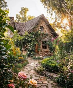 an old stone house surrounded by flowers and greenery in the sunlit garden area