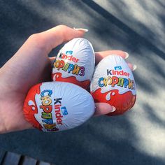 three kinder cupcakes are being held in someone's hand on the street