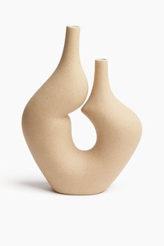 two beige vases sitting side by side on a white surface, one is shaped like a spiral