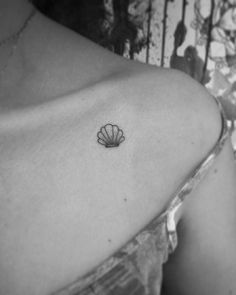 a black and white photo of a woman's shoulder with a shell tattoo on it