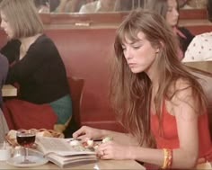 a woman sitting at a table with a book and some food in front of her