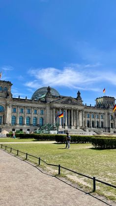 a large building with many flags on it's roof and some people walking in front