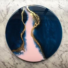 a blue and pink plate with gold designs on the bottom sitting on a marble surface