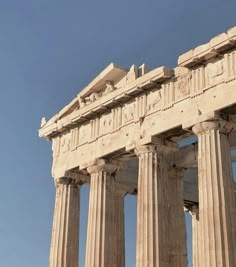 an airplane flying over the top of a tall building with columns on it's sides