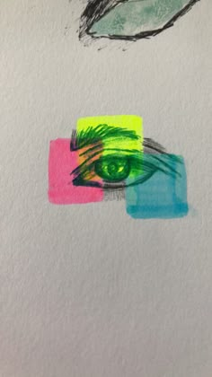 an eye is drawn on paper with colored squares and lines in the foreground, next to a drawing of a pair of green eyes