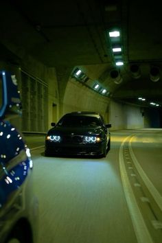 a black car driving down a tunnel with lights on it's headlamps