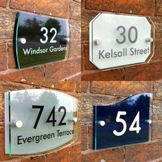 four glass signs on a brick wall with trees in the back ground and sky behind them