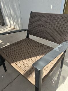 a brown chair sitting on top of a sidewalk next to a white wall and building