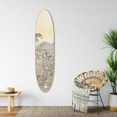 a surfboard hanging on the wall next to a wicker chair and potted plant