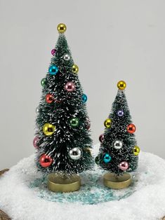 two small christmas trees sitting on top of snow