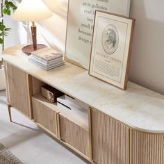 a sideboard with books and magazines on it next to a lamp