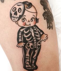 a skeleton tattoo on the leg of a person with a bird flying above it and a little boy wearing a hat