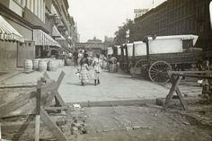 an old black and white photo of people walking down the street