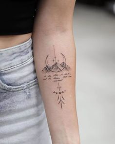 a woman's arm with a tattoo on it and mountains in the distance behind her