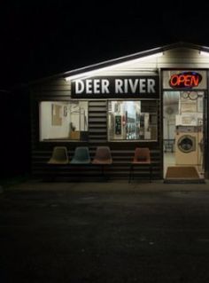 a store front at night with chairs outside