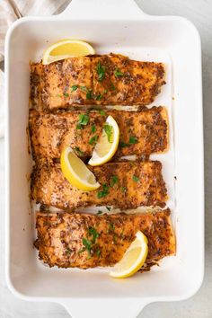 grilled salmon with lemons and parsley in a white casserole dish