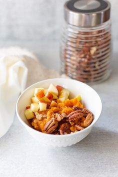 sweet potato bowl with apples and pecans in a white bowl on top of a table