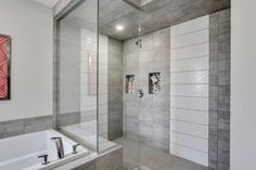 a bathroom with a walk in shower next to a white bathtub and a red painting on the wall