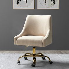 an office chair with wheels in front of two framed pictures on the wall above it