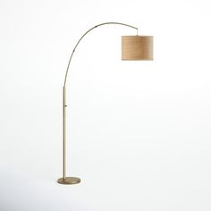 a floor lamp with a beige shade on the side and a white wall behind it