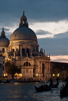 some gondolas are floating on the water in front of an old building at night