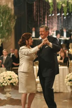 a man and woman dancing together in front of an audience at a formal event with white flowers on the floor