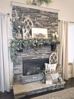 a living room with a stone fireplace and white curtains on the windowsill, decorated for christmas