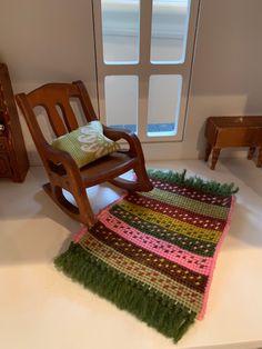 a wooden rocking chair sitting next to a green rug on top of a white counter