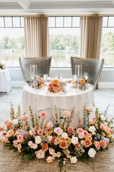 a table with flowers and candles on it in front of two chairs at a wedding reception