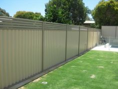 a fenced in backyard with grass and trees