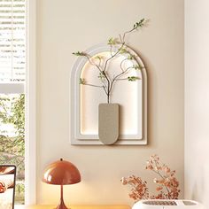 a table with a lamp, mirror and vase on it