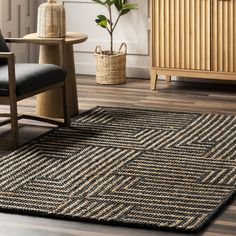 a living room area with a chair, rug and plant in the corner on the floor