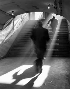 black and white photograph of man walking up stairs