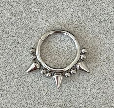 a silver ring with spikes and balls on the inside is laying on a gray surface