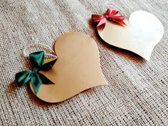 two paper hearts with bows on them sitting on a table