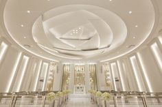 the interior of a modern church with white walls and ceiling lights, decorated with flowers