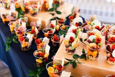 an assortment of appetizers are arranged on a wooden platter with blue table cloth