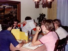 a group of people sitting around a dining room table with papers in front of them