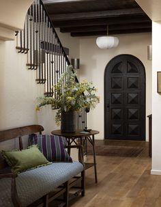 an entryway with stairs and flowers in a vase on the table next to it