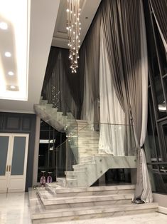 an elegant staircase and chandelier in a modern house with marble floors, walls and ceilings