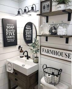 a white bathroom with black and white signs on the wall above the sink, along with two hanging shelves filled with toiletries