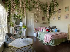 a bedroom decorated in pastel colors with pink and green decor, including flowers hanging from the ceiling